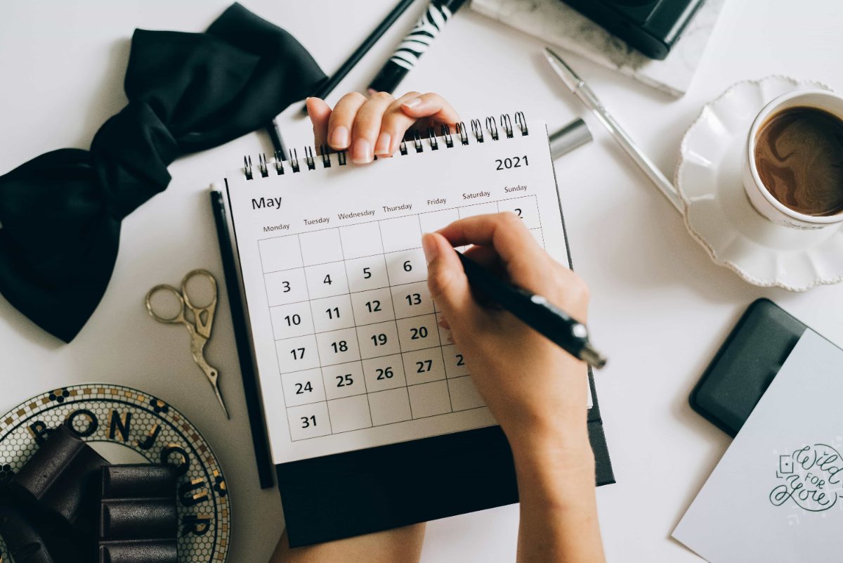 Person writing appointments on a desk calendar
